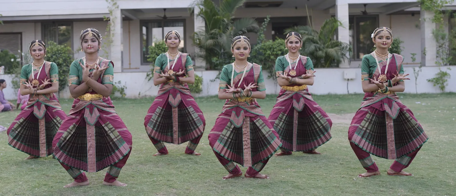 Six students in true, correct aramandi — turned-out, symmetric, grounded — practising on the studio lawn.